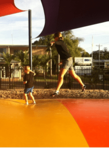 Caleb and his mum and dad are having fun jumping and playing on the jumping pillow in the caravan park in Hervey Bay